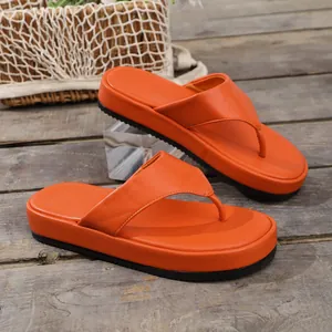 Detalle de sandalias de plataforma naranja vibrante sobre un suelo de madera rústico