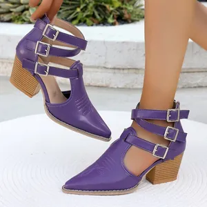 Détail de bottines pointues violettes avec brides à boucle et talon carré façon bois.