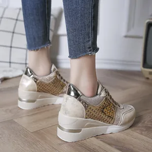 Detailopname van goudkleurige sleehak sneakers met mesh design en glitter details.