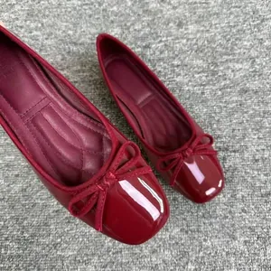 Primo piano delle eleganti ballerine rosse a punta quadrata con dettaglio a fiocco.