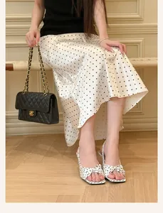 Detail view of elegant white polka dot high heel sandals featuring a chic bow accent