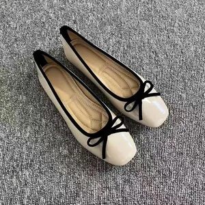 Vista dettagliata di scarpe basse color crema con punta quadrata e fiocco nero