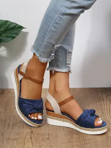 Vista dettagliata di sandali con zeppa in pelle scamosciata blu navy con fiocco e corda