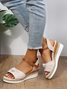 Dettaglio di sandali con zeppa beige con cinturino a nodo e suola in corda intrecciata