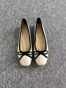 Vista dall'alto di ballerine color crema in stile francese con fiocco nero decorativo