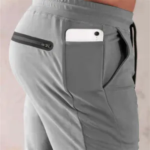 Close-up of men's gray sports joggers featuring a dedicated side phone pocket and zip pocket