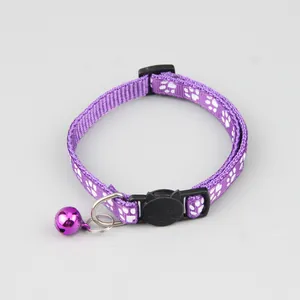 Detail van een paarse stoffen kattenhalsband met een belletje en kattenkop gesp.
