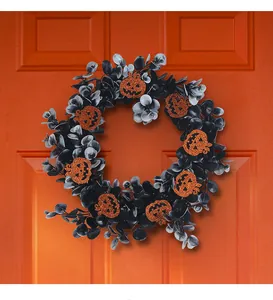 Halloween wreath with black leaves and orange glitter pumpkins on an orange door