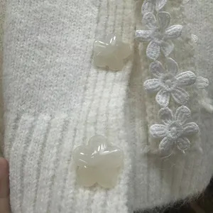 Primo piano del dettaglio di un morbido cardigan bianco in maglia con bottoni a fiore