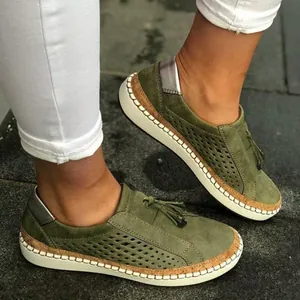 Gros plan sur des mocassins en cuir vert ajouré avec détail de gland et semelle en liège