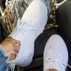 Close-up view of white fly-knit breathable mesh women's sneakers with lace-up design.