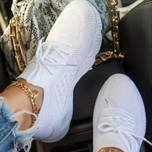 Close-up of white breathable mesh fly-knit sneakers for women with stylish gold anklet detail.