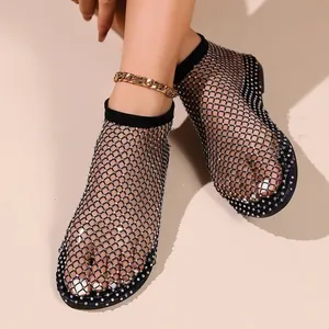 Détail de sandales élégantes en filet noir ornées de strass brillants et étincelants.