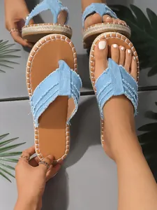 Nahaufnahme von blauen Denim-Flip-Flops mit Fransen und stilvollen weißen Ziernähten.