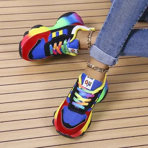 Dettaglio di sneaker platform colorate con lacci arcobaleno e cavigliere dorate