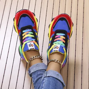 Vista dettagliata di sneakers arcobaleno con lacci colorati e cavigliere color oro lucido
