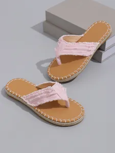 Detaillierte Nahaufnahme von rosa Flip-Flops mit Fransen und dekorativen weißen Ziernähten.