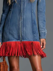Close-up of a blue denim mini skirt featuring vibrant red fringe and front zipper detail