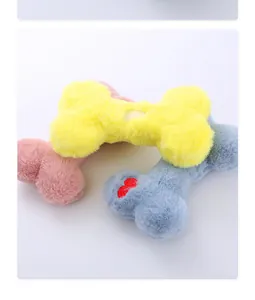 Dettaglio che mostra morbidi peluche per cani a forma di osso con ricamo a cuore