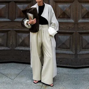 Street style shot of a light apricot loose trench coat with wide lapels and satin lining.