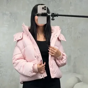 Street style pink hooded short puffer jacket worn by a model in a casual mirror selfie setup.
