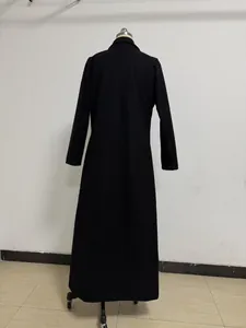 Back view of a long black wool coat displayed on a mannequin against a white wall.