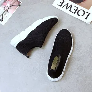 Close-up detail of women's breathable black knit slip-on sneakers with white soles