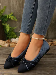 Detailed view of blue knitted flat shoes with a stylish bow on a wooden surface.