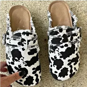 Détail de sabots imprimé vache noir et blanc avec sangle à boucle réglable