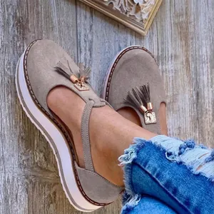 Detalle de sandalias de plataforma en ante gris con borlas y hebilla dorada elegante