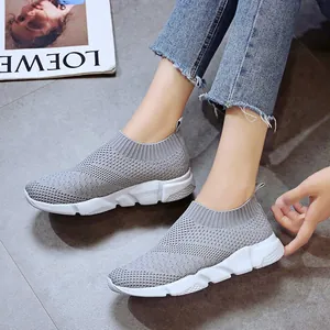 Detailed view of grey breathable fly-knit slip-on sneakers with thick white sole