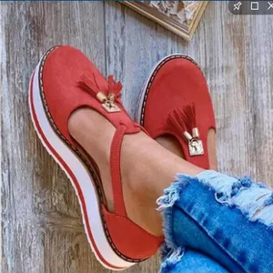 Detalle de sandalias de plataforma en ante rojo con borlas y tira al tobillo