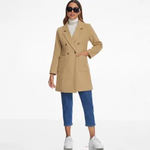 Modell präsentiert einen kamelfarbenen zweireihigen Wollmantel mit lässigen Jeans.