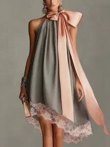 Dettaglio di un abito a pieghe grigio con fiocco rosa e bordo in pizzo elegante