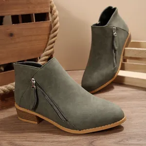 Detailed view of olive green suede-like ankle boots featuring side zipper and low block heel
