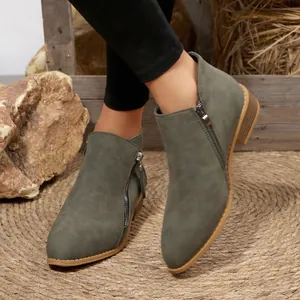 Detailed view of stylish olive green pointed-toe ankle boots with side zippers on model