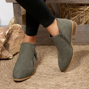 Detail view of women's olive green suede pointed-toe ankle boots with stylish side zippers.