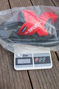 Détail de sandales de sport rouges pesées sur une balance numérique à 120 grammes