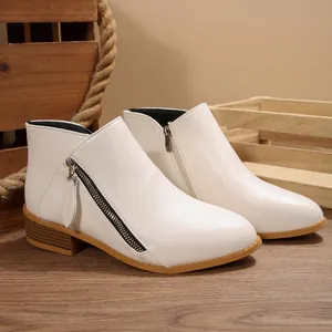 Detail showing the zipper and faux leather texture of white pointed-toe ankle boots
