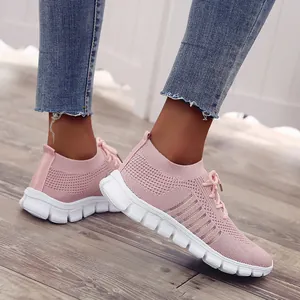 Seitenansicht der rosa Fly-Knit-Sneaker mit weißer Plateausohle auf Holzboden
