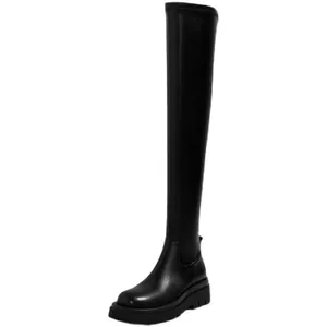 Detalle de vista lateral de botas elásticas negras sobre la rodilla con suela plana gruesa