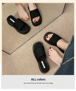 Detailopname van zwarte plateauslippers gedragen op een beige getextureerd tapijt