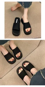 Gedetailleerd overzicht van zwarte plateauzolen slippers met dikke zool voor dames.