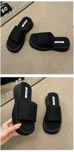 Detailweergave van stijlvolle zwarte plateau-slippers voor dames met een textuurband.