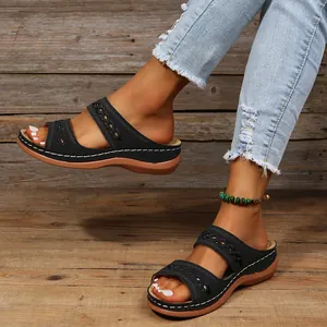 Détail de sandales compensées vintage noires pour femmes avec coutures sur sol en bois