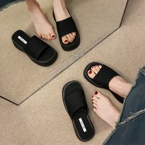 Modieuze zwarte plateau slippers voor dames met een dikke zool en breed band ontwerp.