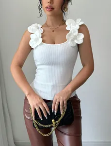 Dettaglio del top a maglia bianco con eleganti fiori 3D sulle spalline decorative.
