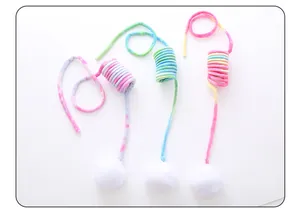 Vue détaillée de jouets pour chats en peluche arc-en-ciel avec de doux pompons blancs
