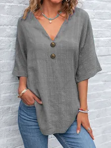 Dettaglio del top grigio da donna con scollo a V, bottoni in legno e tessuto.