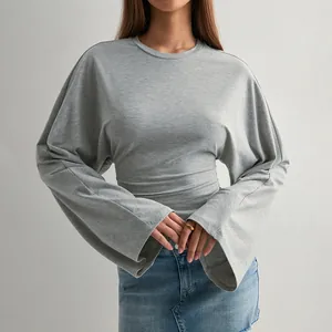 Detailansicht eines grauen Langarmshirts mit weiten Ärmeln und tailliertem Schnitt.